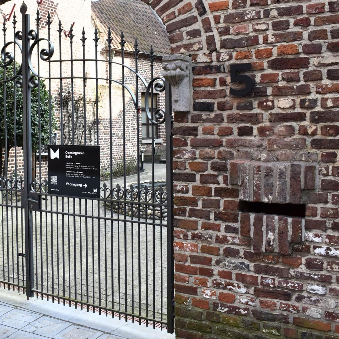 Toegangspoort met informatiebord bij historische locatie.