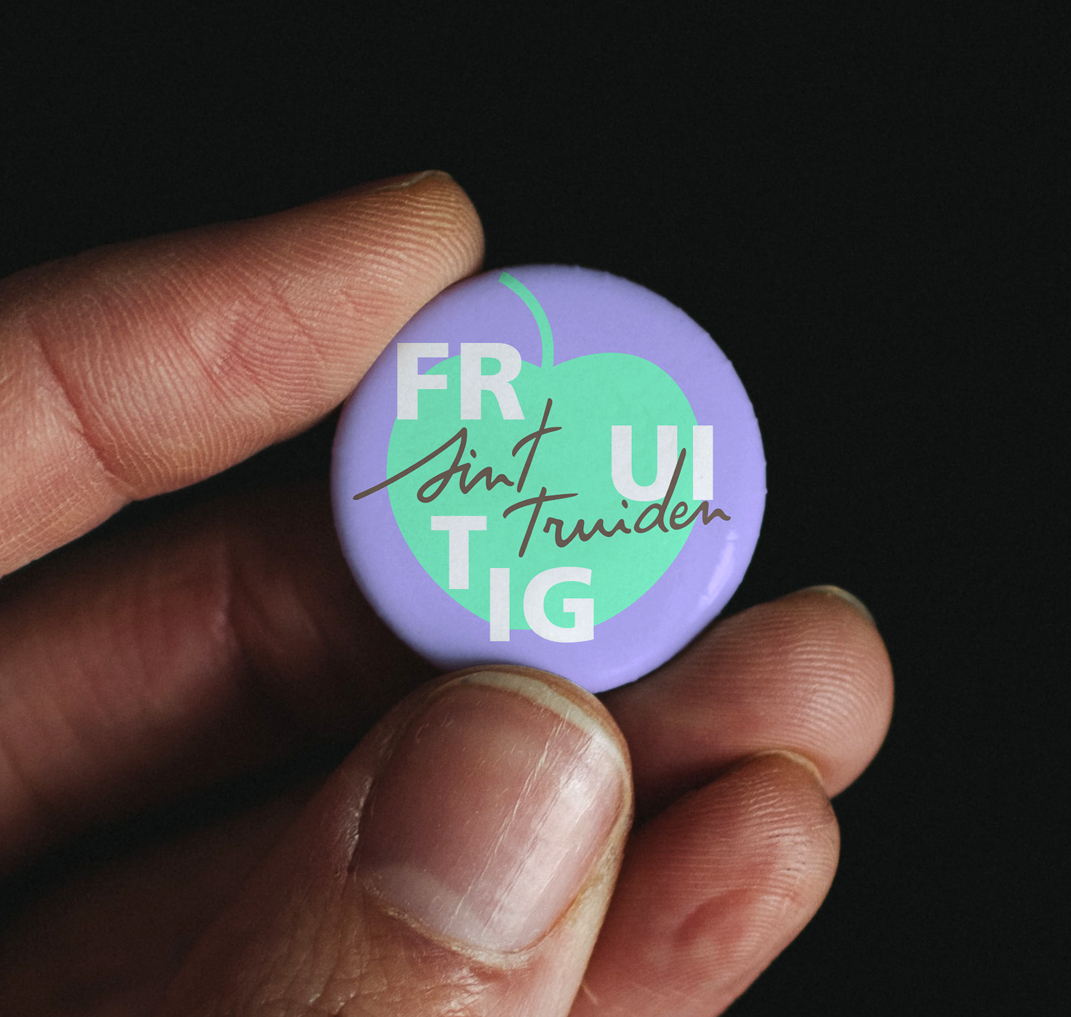 Hand houdt badge met tekst 'Fruitig Sint-Truiden'
