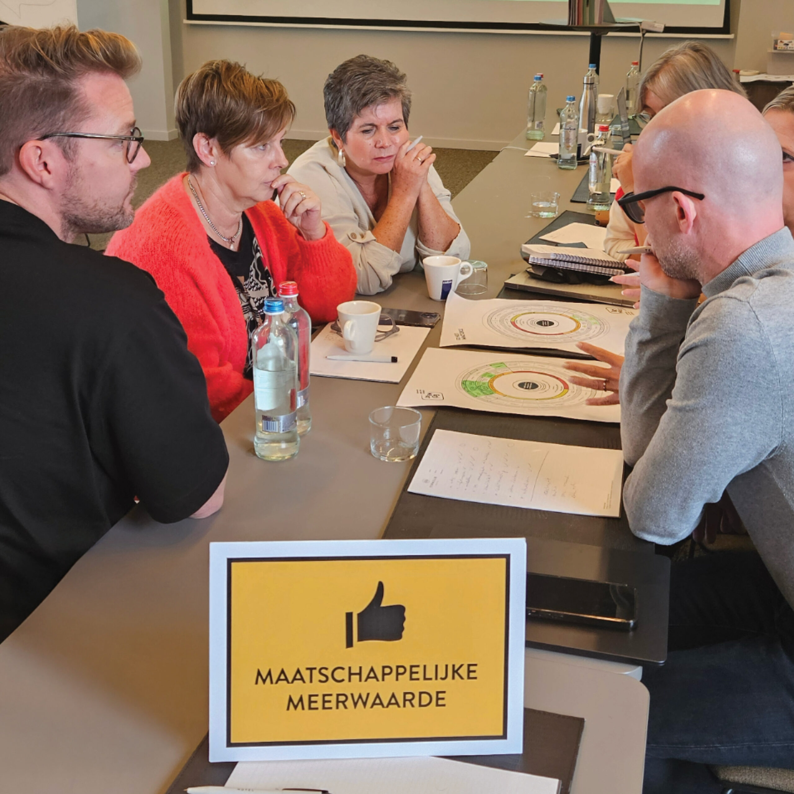 Groepsdiscussie over maatschappelijke meerwaarde in vergaderruimte.