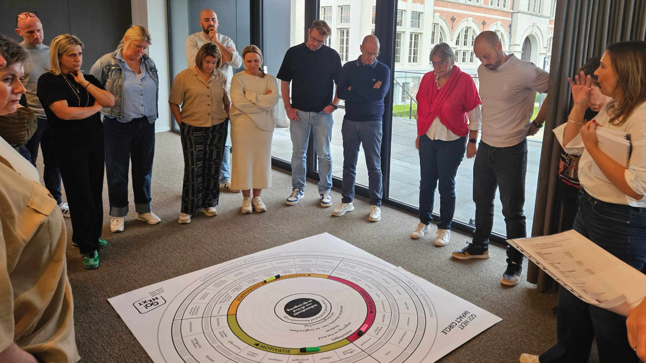 Groep mensen observeert gekleurd diagram op de grond.