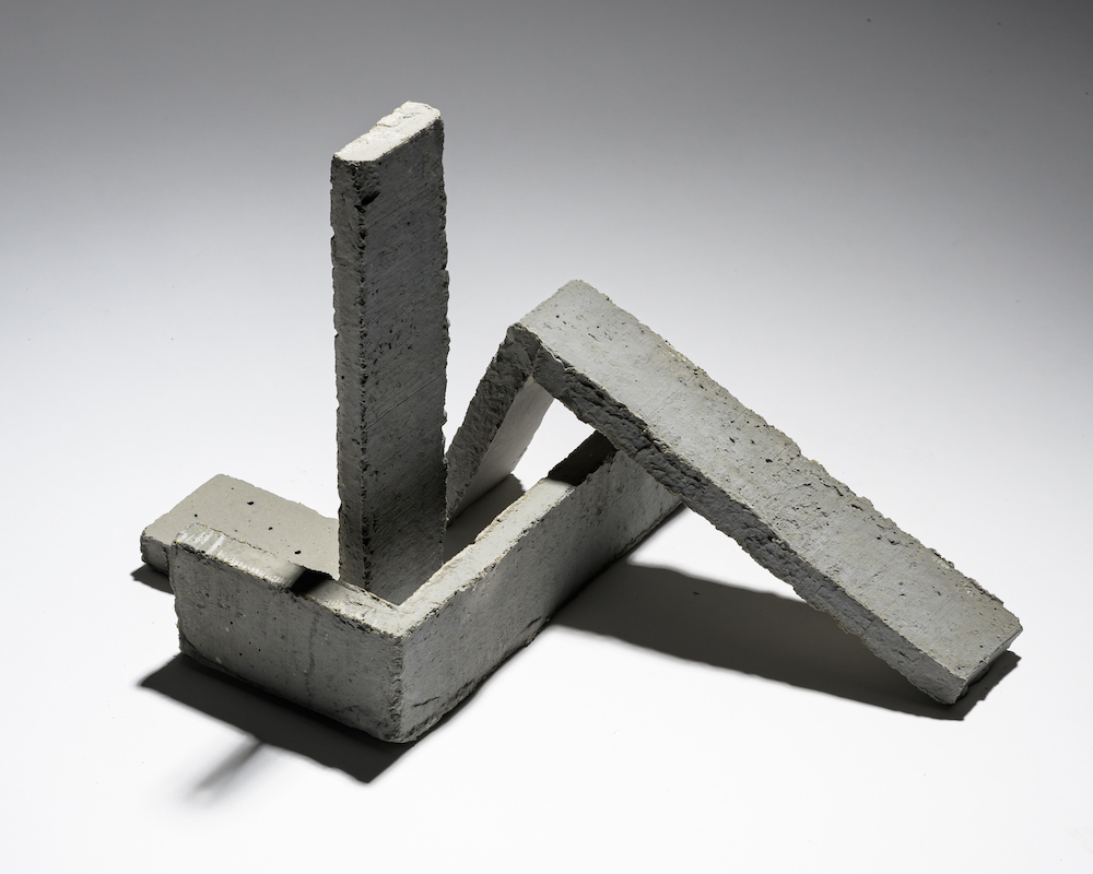 Abstracte sculptuur van betonnen blokken op witte achtergrond.